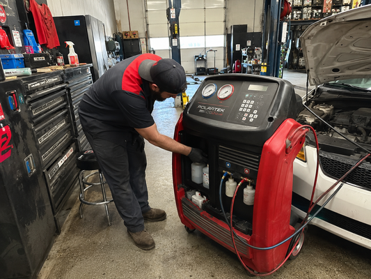 Technician inspecting the oil injection system on an automotive A/C service machine