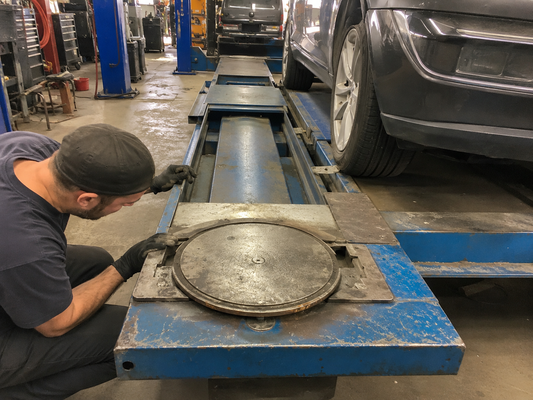 Technician inspecting sticking turn plates on an automotive alignment rack